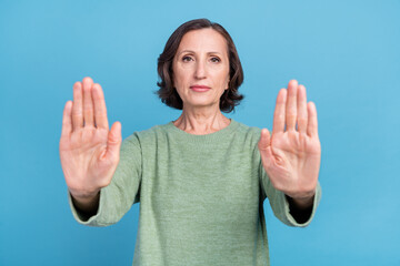 Photo of old grey hair woman show stop gesture emotion wear green jumper isolated on blue color background