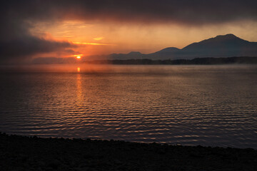 Wall Mural - Colorful sunrise over morning lake. Mountains at background