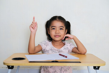 Wall Mural - Asian little girl raise her finger up when study