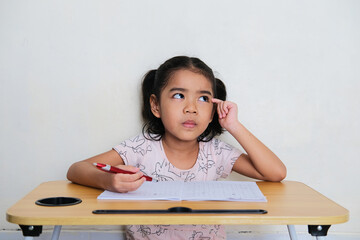 Wall Mural - Asian little girl showing thinking gesture during study