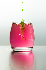 Poster - Vertical shot of a glass of pink water with splashes and green paint