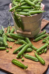 Wall Mural - Pods of green peas with leaves in bowl on wooden table