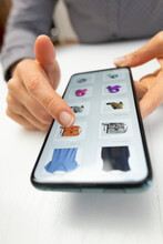 Shopping For Clothes In Online Stores Using A Mobile Phone. Hands Of A Woman Choosing A Product On A Smartphone Screen. E-commerce.	