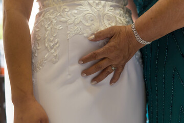 Mother of the bride touching the pregnant belly of the bride in the morning before the ceremony, photos at the wedding celebration