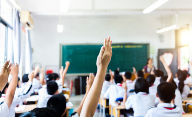 rear view of raised hands in middle school classroom