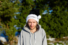 A Grumpy Young Man Wearing A Black Santa Hat With The Words Bah Humbug Written On It