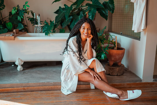 black woman relaxing in her room wearing a white robe