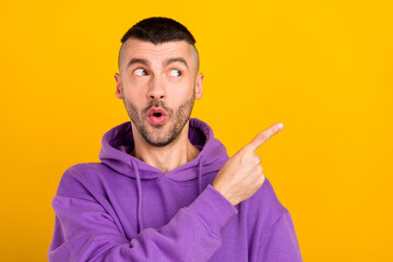 Wall Mural - Photo portrait young man wearing purple hoody curious pointing copyspace isolated vibrant yellow color background