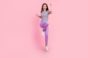 Poster - Photo of lucky pretty young lady wear striped outfit smiling jumping high rising fists isolated pink color background