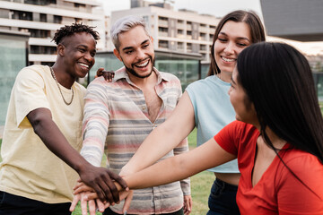 Young diverse group of people celebrating together stacking hands outdoor - Focus on gay man wearing makeup