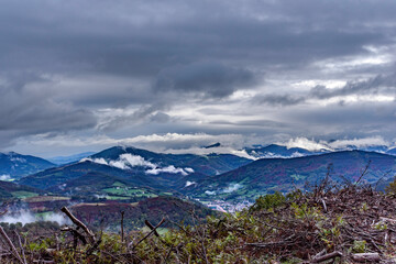 Wall Mural - Landscape of green and brown winter mountains full of low white clouds stuck to the ground. Completely cloudy dark sky, dark gray, on a rainy autumn morning. In the background the valley.