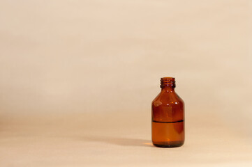 Brown glass bottle with medicine liquid on beige paper background