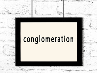 Black frame hanging on white brick wall with inscription conglomeration