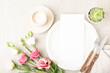 Elegant summer, spring table setting design with pink ans white flowers, cutlery, tablecloth, candle, empty plate and on beige table. Blank card mockup. Restaurant menu template. Top view, flat lay