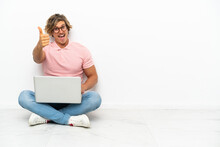 Young Caucasian Man Sitting On The Floor With His Laptop Isolated On White Background With Thumbs Up Because Something Good Has Happened