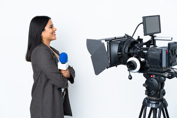 Wall Mural - Reporter Colombian woman holding a microphone and reporting news on white background in lateral position