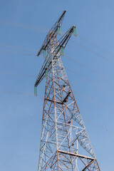 Big electricity tower, bottom-up view, with blue sky in the background