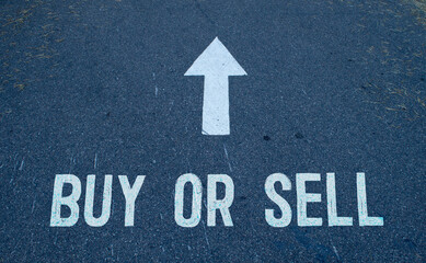 Business concept. On the asphalt road markings an arrow with the inscription - BUY OR SELL.