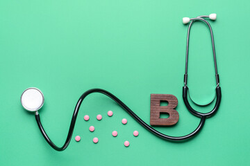 Letter B with stethoscope and pills on color background