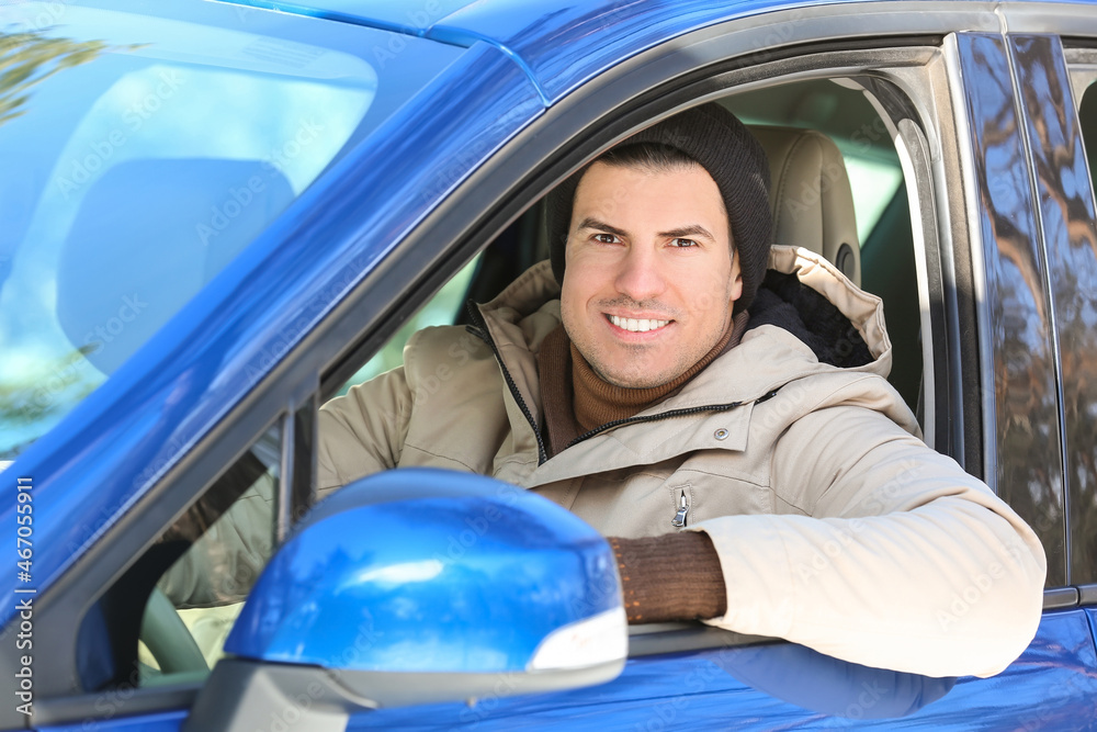 Young man sitting in car on winter day