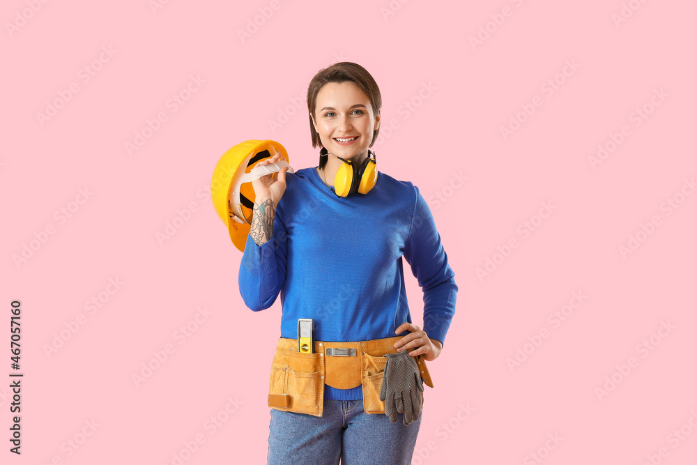 Female construction worker with hardhat on pink background
