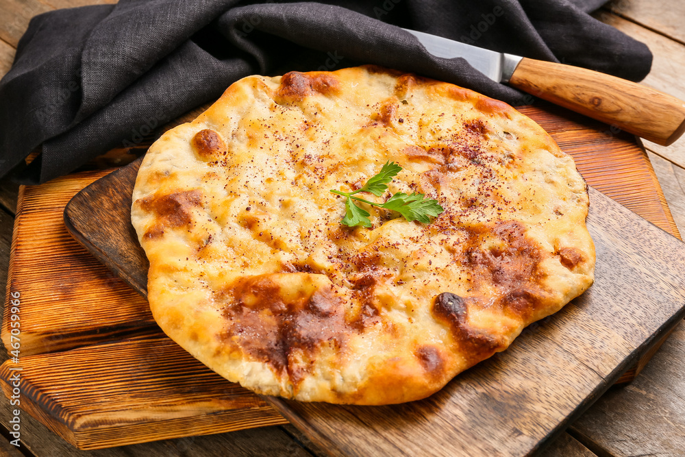 Board with tasty khachapuri on wooden background, closeup