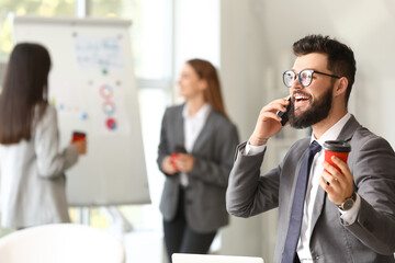 Canvas Print - Man talking by phone while having coffee break in office