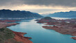 Aerial flight Beautiful spring landscape of river with blue turquoise water and hills against background of mountains and dawn sky. Bare rocky shores are visible due to ow water level on the lake.