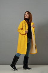 Wall Mural - Happy caucasian girl in yellow raincoat and boots