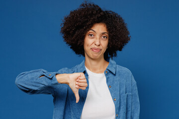 Poster - Young displeased upset unhappy black woman in casual clothes shirt white t-shirt showing thumb down dislike gesture isolated on plain dark blue background studio portrait. People lifestyle concept