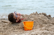 A Young Boy Is Buried In The Sand On The Shores Of Lake Michigan Usa