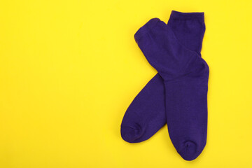 Wall Mural - Pair of violet socks on yellow background