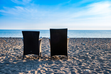 two chairs standing next to each other on the seashore in the sand. rest together