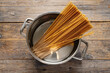 Cooking spaghetti pasta in pot on table