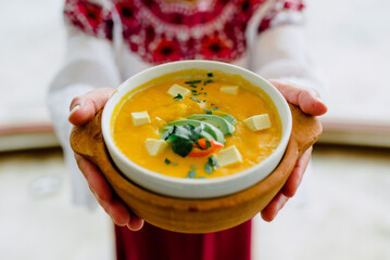 Wall Mural - Bowl of delicious, healthy soup with avocado on the palm of someone