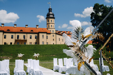 Wall Mural - Decorated wedding arch on the background of an ancient castle.Wedding ceremony with an arch decorated with feathers in retro style