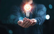 © Dilok - Businessman holding glowing light bulb with mechanical gear and orange light ray for inspiration creative thinking idea and future innovation technology  concept.