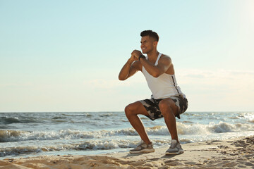 Canvas Print - Sporty man doing exercise on sandy beach at sunset