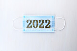 Fototapeta  - Medical mask with numbers 2022 Tiger on white wooden background. Coronavirus infection control concept. Symbol 2022 Tiger .