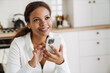 © Drobot Dean - Young black woman using cellphone and smiling at home
