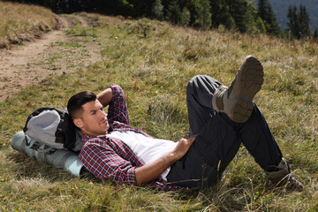 Poster - Tourist with backpack and camping mat resting on ground