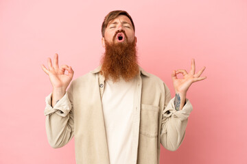 Wall Mural - Young reddish caucasian man isolated on pink background in zen pose