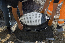 A Worker Installs A Sewer Manhole On A Septic Tank Made Of Concrete Rings