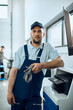 © Drazen - Young mechanic uses desktop PC at car workshop and looks at camera.