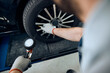© Drazen - Close-up of mechanic uses pressure gauge while examining car tire in a workshop