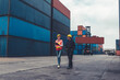 © InfiniteFlow - Industrial worker works with co-worker at overseas shipping container yard . Logistics supply chain management and international goods export concept .