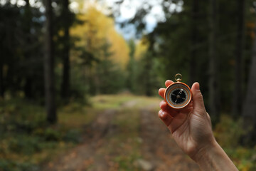 Woman using compass during hiking in forest, closeup