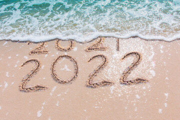 Wall Mural - message year 2021 replaced by 2022 written on beach sand background. good bye 2021 hello to 2022 hap