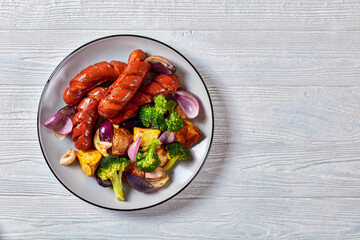 Sausage and vegetables on white wooden background