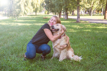 Wall Mural - woman hugs her retriever in the park outdoors.